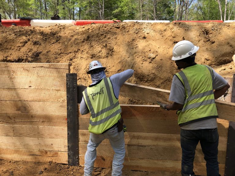 workers doing drilled casing and lagging wall